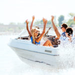 Cheerful young people riding in a speedboat.